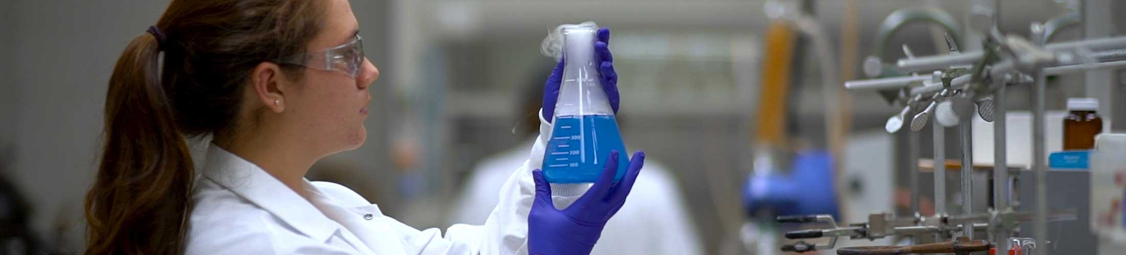 Female student holding a beaker in lab.