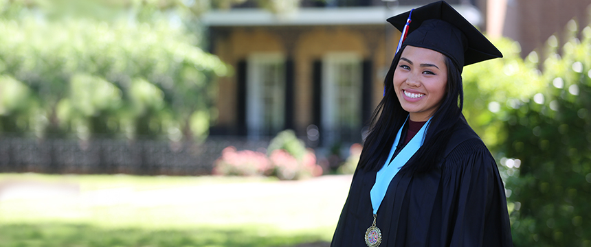 Female student in graduation cap and gown smiling