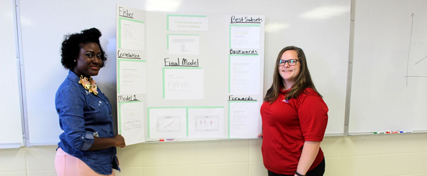 Two mathstat students standing in front of project.