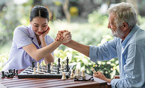 A woman playing chess with an older man.