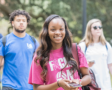 Female student smiling walking on a campus.