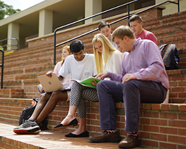 A group of students studying outside on steps on campus.