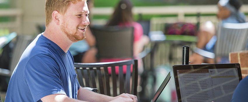 Student working on laptop outside