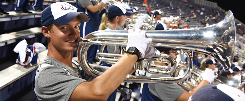 Student playing trumpet in the stands