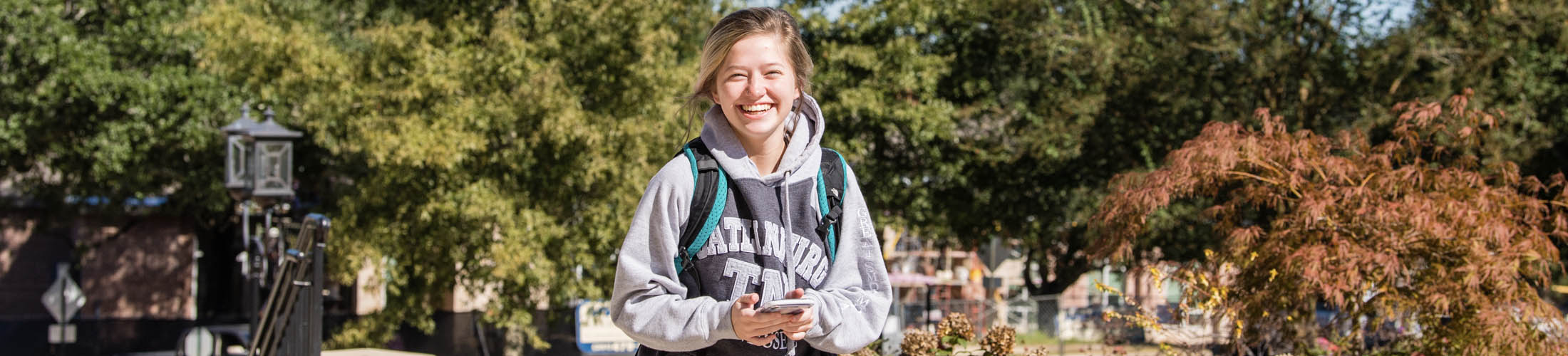Female student smiling wearing backpack walking on campus.