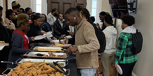Black Alumni Society Community Engagement Lunch with members getting food in buffet line.