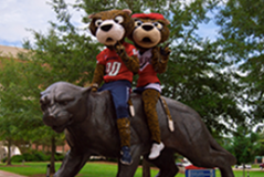 Southpaw and Miss Pawla sitting on the jaguar statue in front of the Mitchell Center. 