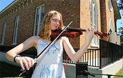 Female student playing violin outside of Bethel