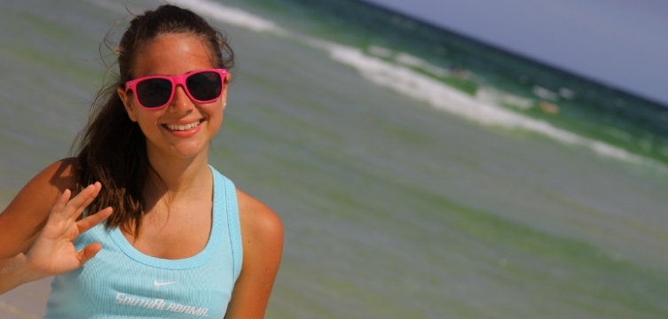 Student in sunglasses smiling on the beach.