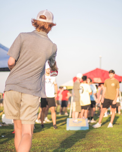 Student playing corn hole outside at an IFC event.