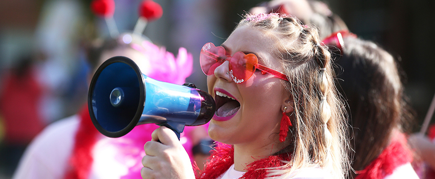 Sorority member yelling into microphone at bid day.