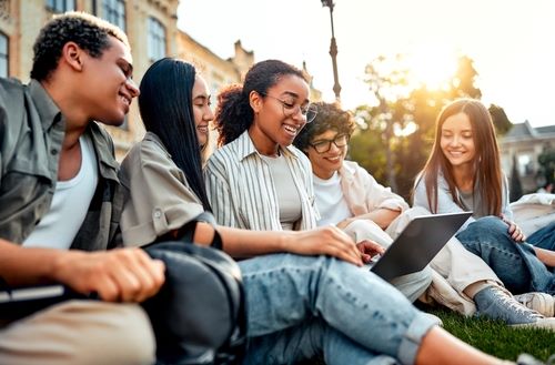 Students sitting on steps looking at laptop.