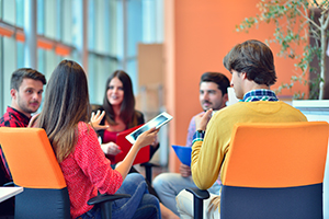 Group sitting in circle talking with one person holding a tablet.