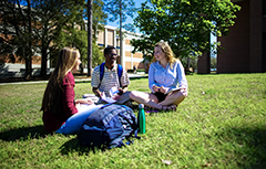 Three students sitting on ground at campus