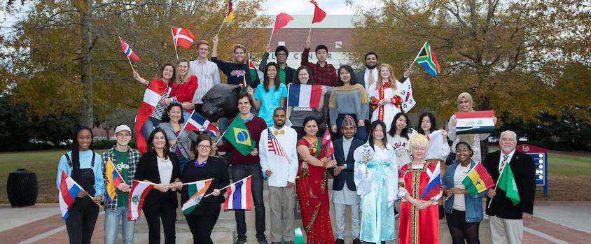 International Students in front of the Mitchell Center with flags
