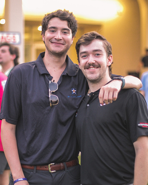Two IFC members with their arm over each other outside at an event.
