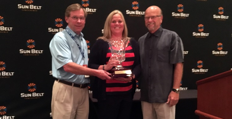 Dr. John Smith, left, USA executive vice president; Jinni Frisbey, USA associate athletic director of sports medicine and senior woman administrator; and Sun Belt Commissioner Karl Benson are pictured with the Bubas Cup, which was awarded to South Alabama for the second year in a row.  data-lightbox='featured'