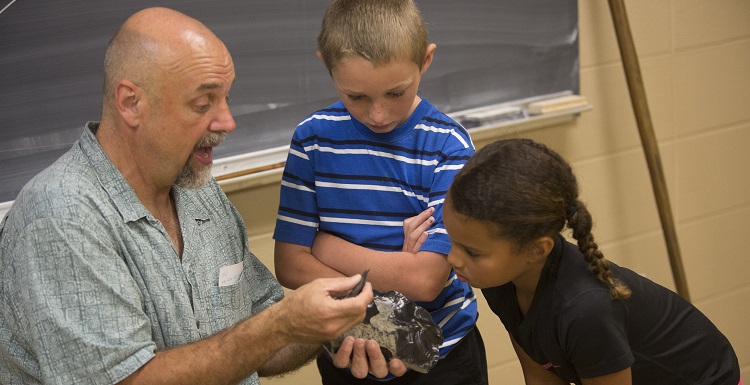 Dr. Phil Carr, Chief Calvin McGhee Endowed Professor of Native American Studies, gives a hands-on archaeology lesson to Kolby Rayborn and Kylie Langham during Art and Archaeology Day. data-lightbox='featured'