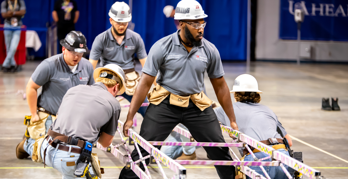 University of South Alabama College of Engineering students successfully construct a steel bridge in the Mitchell Center that would support 2,500 pounds.