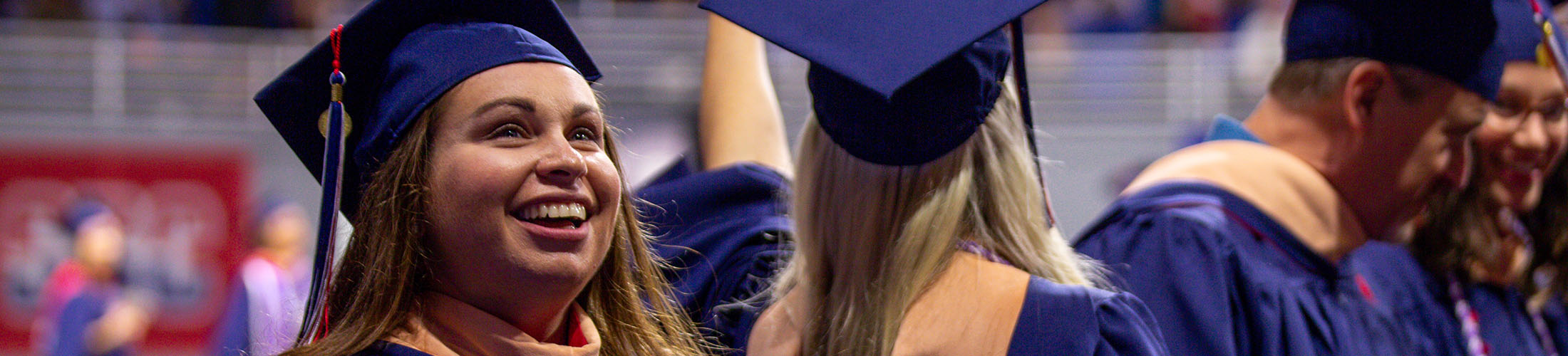 Female student at graduation looking up and smiling in her cap and gown.